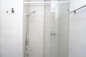 Eine Dusche mit Handbrause, Wandarmatur und einer Duschkabine aus Glas.