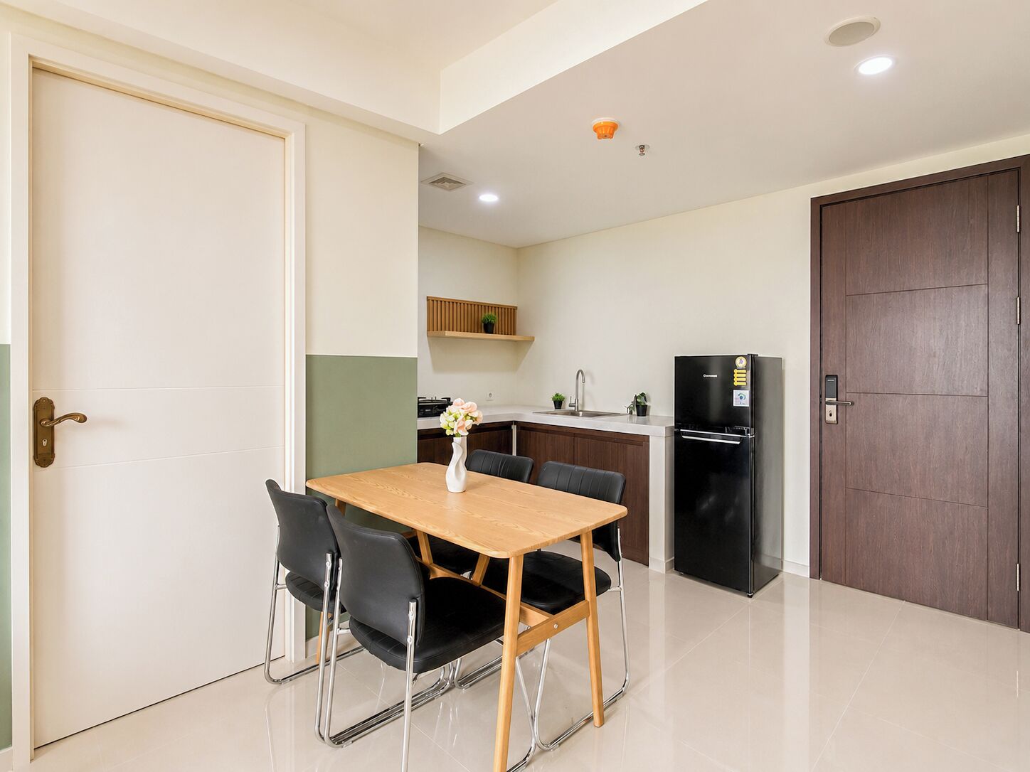 A modern kitchen with a dining area, including a table with chairs and a refrigerator.