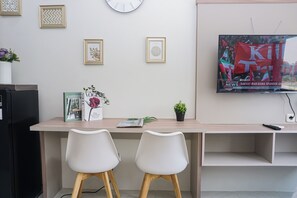Ein modernes Wohnzimmer mit Fernseher, zwei weißen Sesseln, einem kleinen Tisch und Dekoration.