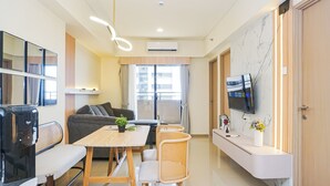 Een moderne woonkamer met een bank, een eettafel en een aan de muur bevestigde televisie.