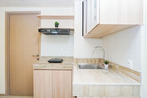 A compact kitchen with a built-in oven, a sink, and a countertop. - Cozy And Functional 3Br At Apartment Meikarta (Cikarang)