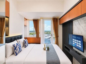 Ein Hotelzimmer mit Bett, Fernseher und Blick auf die Stadt.