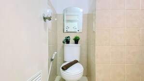 A small, clean bathroom with a toilet, a hand dryer, and a small potted plant on the wall. - Nice And Warm Studio Room At Apartment Green Bay Pluit (Jakarta)