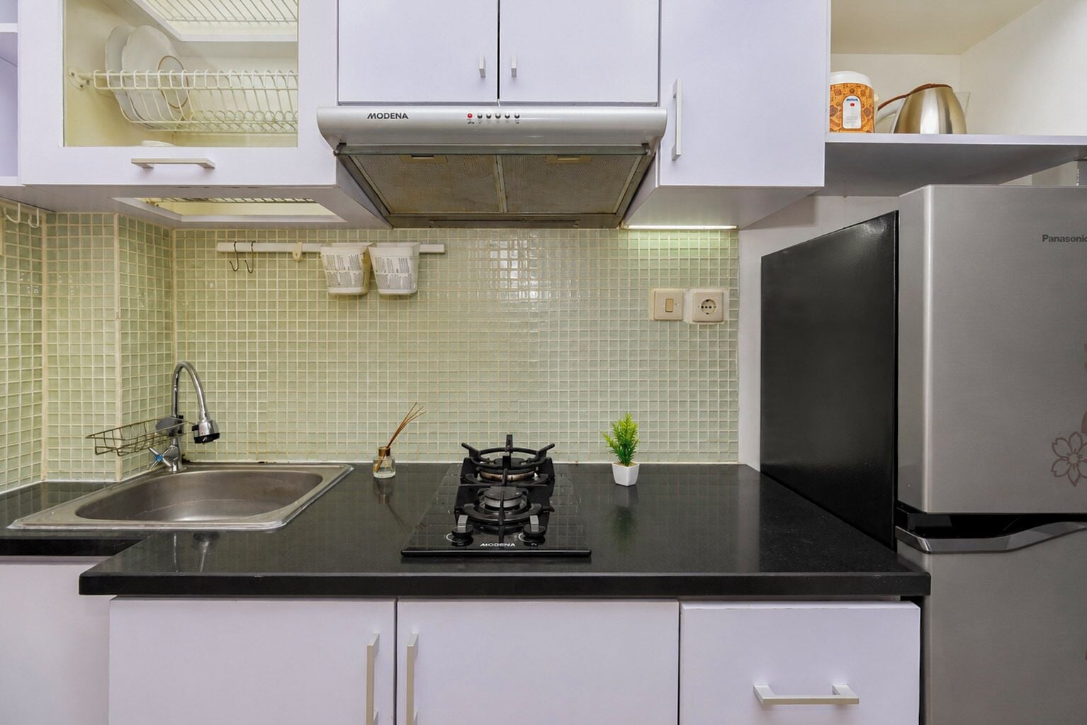 A kitchen with white cabinets, a stainless steel sink, a gas stove, and a refrigerator.