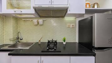 A kitchen with white cabinets, a stainless steel sink, a gas stove, and a refrigerator.