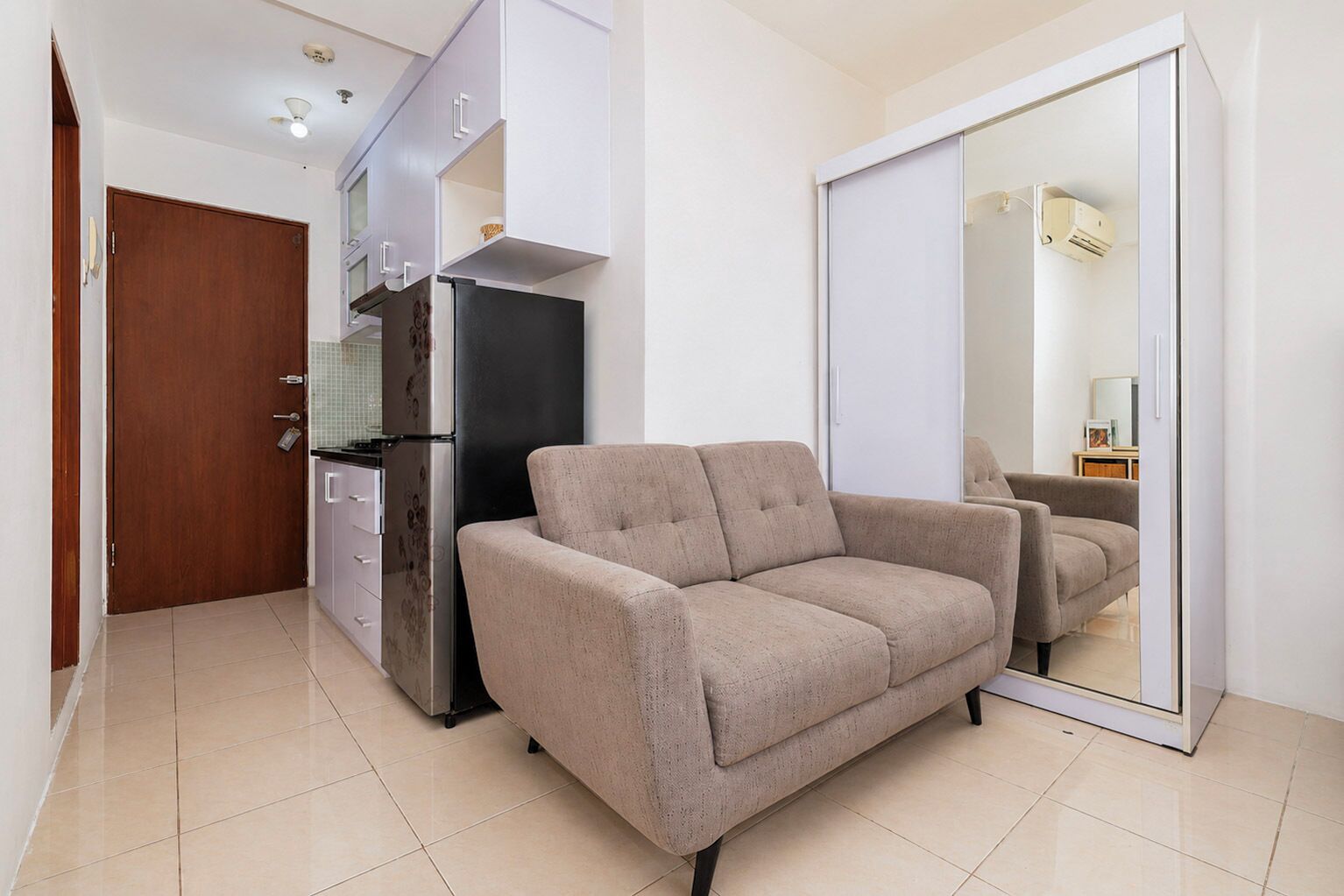 Un espacio habitable compacto con kitchenette, un sofá y un armario con puerta corredera.