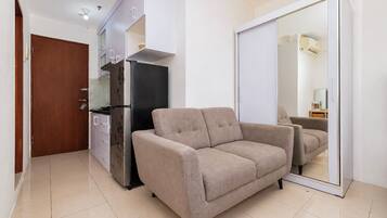 Un espacio habitable compacto con kitchenette, un sofá y un armario con puerta corredera.
