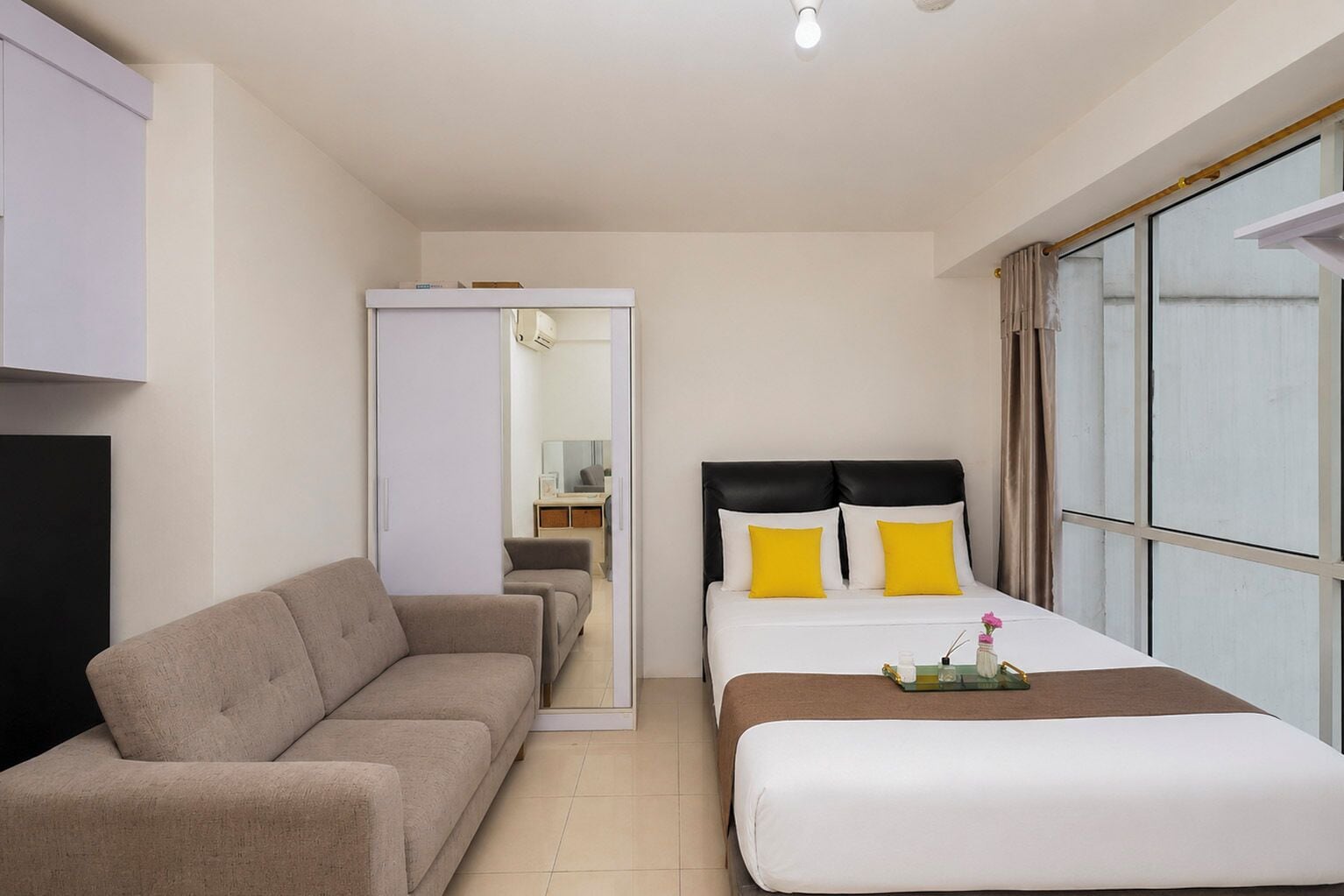 Ett hotellrum med en säng, en soffa, ett skrivbord och ett fönster.