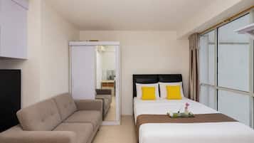 A hotel room with a bed, a sofa, a desk, and a window.
