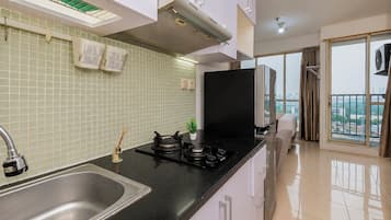 Une cuisine moderne équipée d’une cuisinière à gaz, d’un évier et d’une fenêtre donnant sur un paysage urbain.