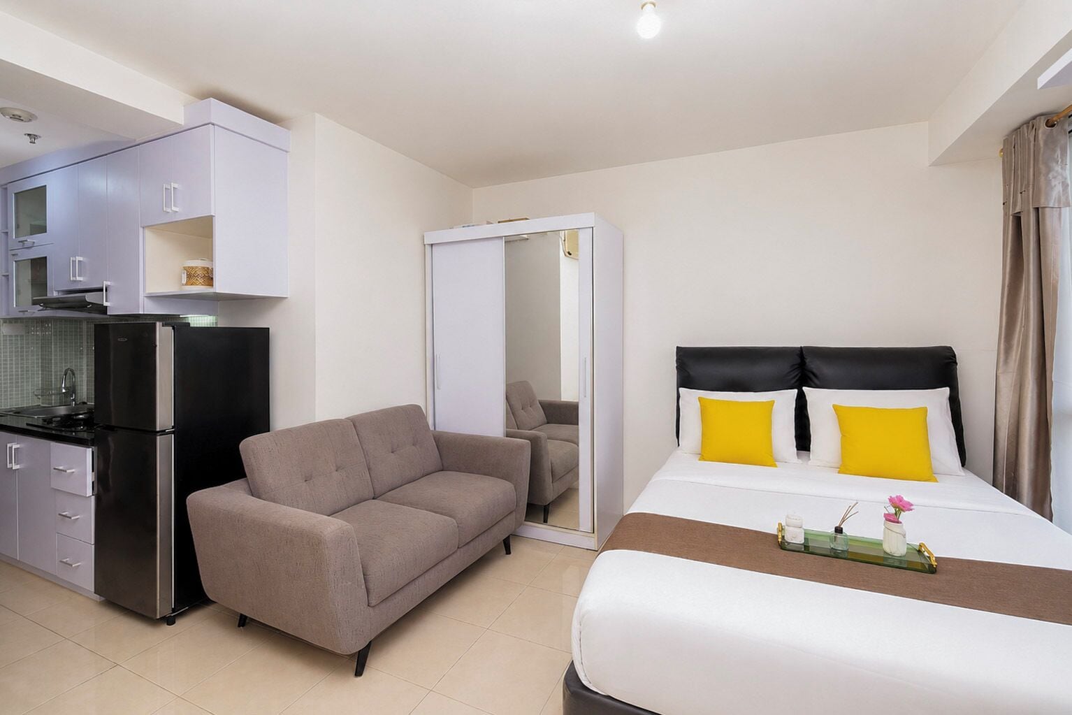 Una habitación de hotel con cama, sofá, kitchenette y baño.