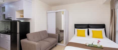 Una habitación de hotel con cama, sofá, kitchenette y baño.