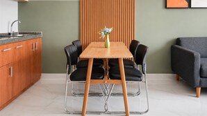 A modern kitchen with a wooden table, black chairs, and a vase with flowers. - Refined 2Br At Apartment Transpark Bintaro (Tangerang)