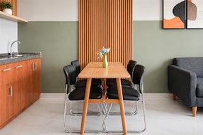 A modern kitchen with a wooden table, black chairs, and a vase with flowers. - Refined 2Br At Apartment Transpark Bintaro (Tangerang)