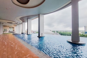 A modern indoor pool with a curved ceiling and large pillars, surrounded by a tiled walkway. - Refined 2Br At Apartment Transpark Bintaro (Tangerang)