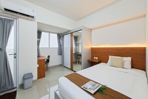 A hotel room with a bed, bedside table, and a desk with a chair. - Functional Simple Studio Room At Apartment Cisauk Point (Cisauk)