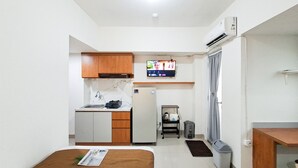 Ein kompaktes Hotelzimmer mit einer Küchenzeile, einem Bett, einem Fernseher und einem kleinen Badezimmer.