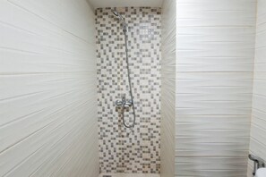 A shower with a tiled wall and a metal showerhead. - Functional Simple Studio Room At Apartment Cisauk Point (Cisauk)