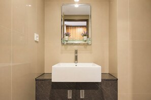 A bathroom with a white sink, a glass shelf above it, and a mirror. - Modern Breezy Studio At Apartment Tamansari Skylounge Balikpapan (Balikpapan)
