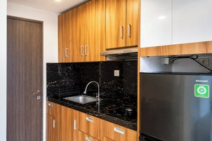 A kitchen with wooden cabinets, a black marble countertop, a stainless steel sink, and a refrigerator with a green sticker.