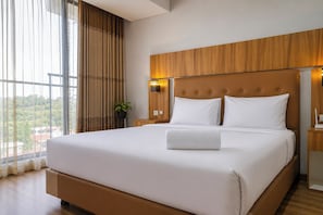 Una cama grande con cabecera de madera, ropa de cama blanca y una mesita de noche con lámpara.