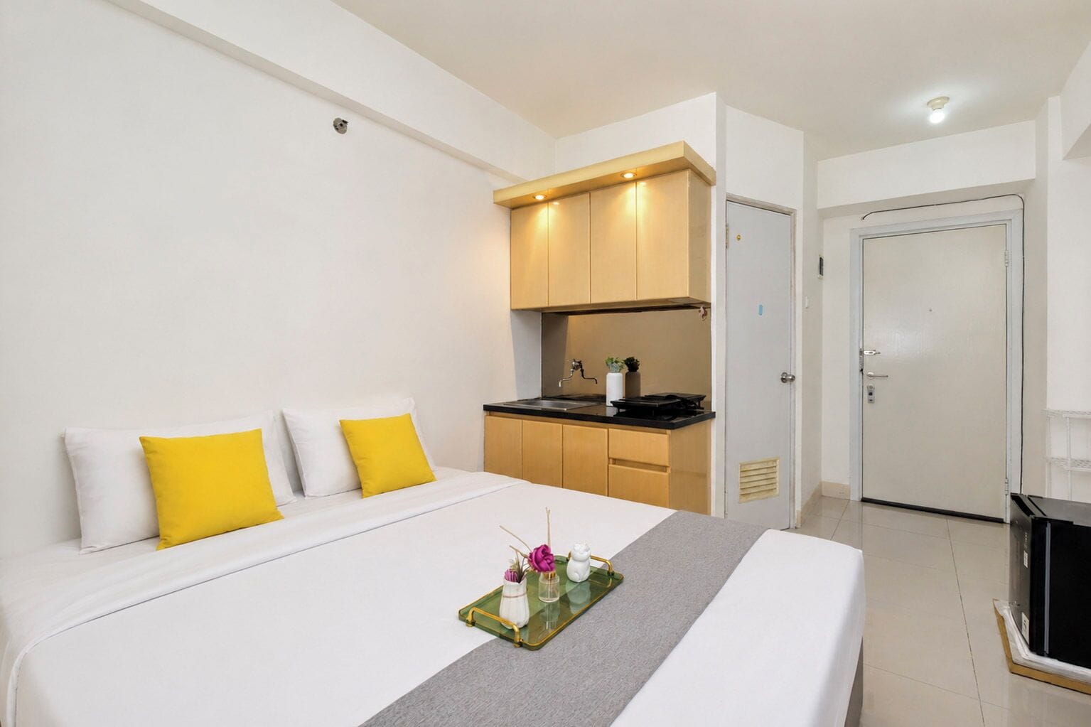 Una habitación de hotel con cama, una kitchenette pequeña y una puerta.