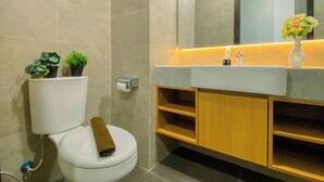A modern bathroom with a toilet, a sink, and a mirror. - Cozy Living Studio At Apartment Saffron Noble (Bogor)