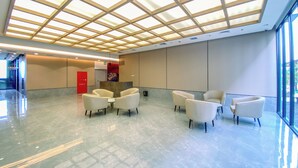 A spacious lobby with a high ceiling, a reception desk, and seating area. - Cozy Living Studio At Apartment Saffron Noble (Bogor)