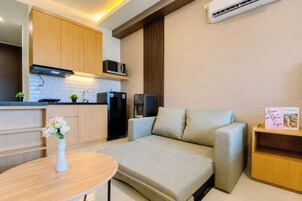 A compact living space with a kitchenette, a sofa, a small table, and a decorative item on a shelf.