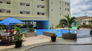 Un patio de hotel con piscina, mobiliario exterior y plantas en macetas.