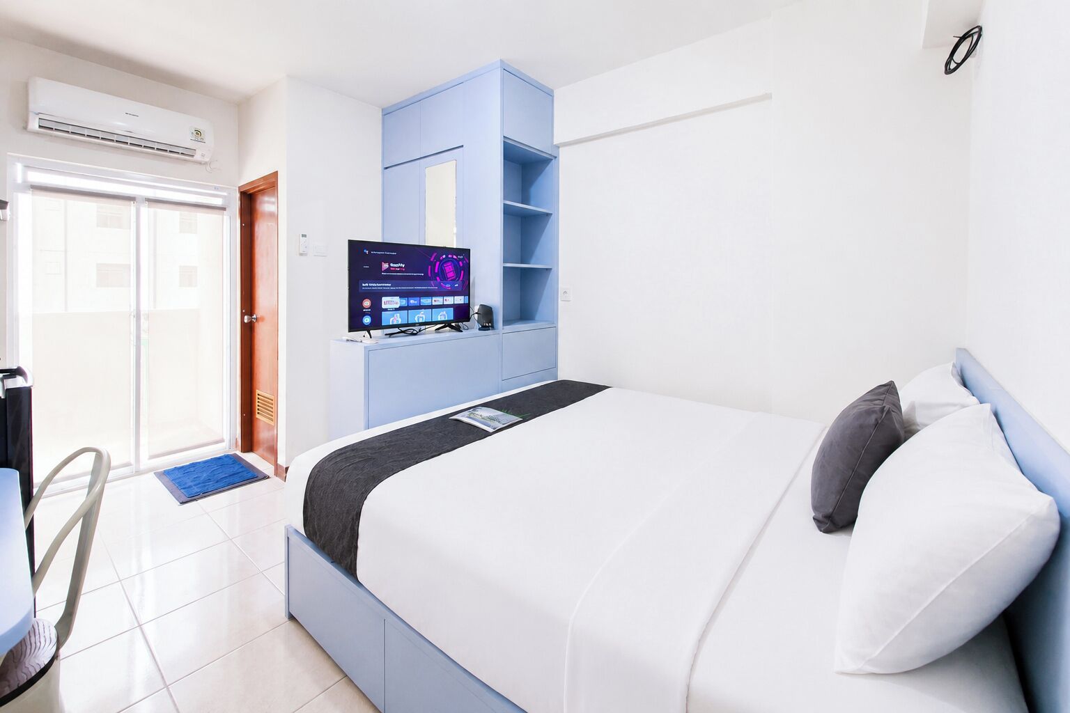 Quarto de hotel moderno com cama, televisão, escrivaninha e janela.