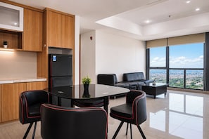 Eine moderne Küche mit Kühlschrank, einem Esstisch mit Stühlen und Blick auf die Stadt durch große Fenster.