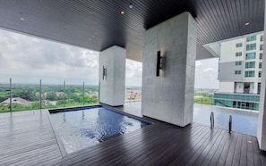 Ein moderner, überdachter Pool mit Holzterrasse, großen Säulen und Blick auf die Stadt.