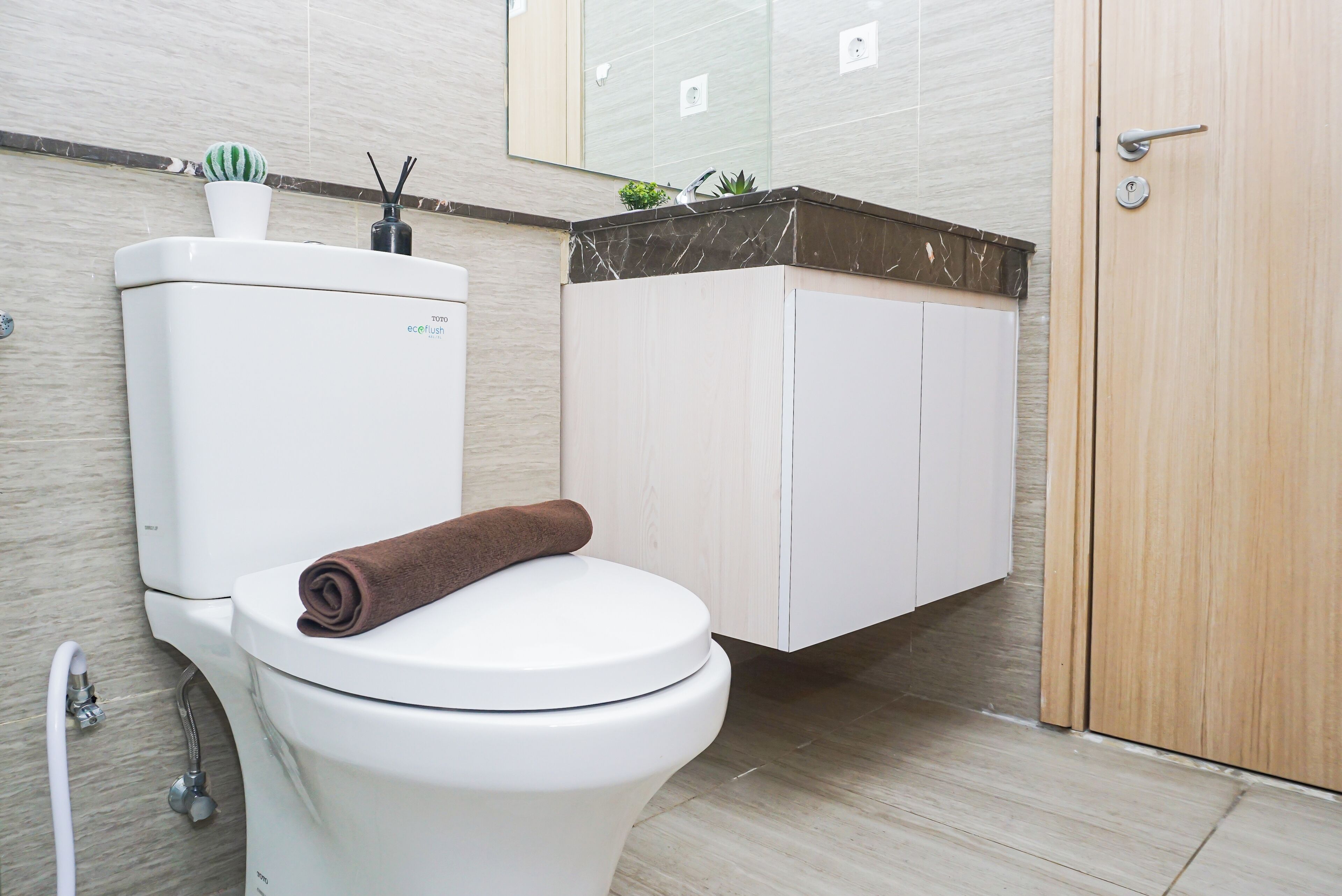 Un baño moderno con inodoro, toalla, armario y espejo.