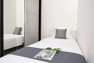 Un dormitorio moderno con cama, mesita de noche, una revista y una planta.