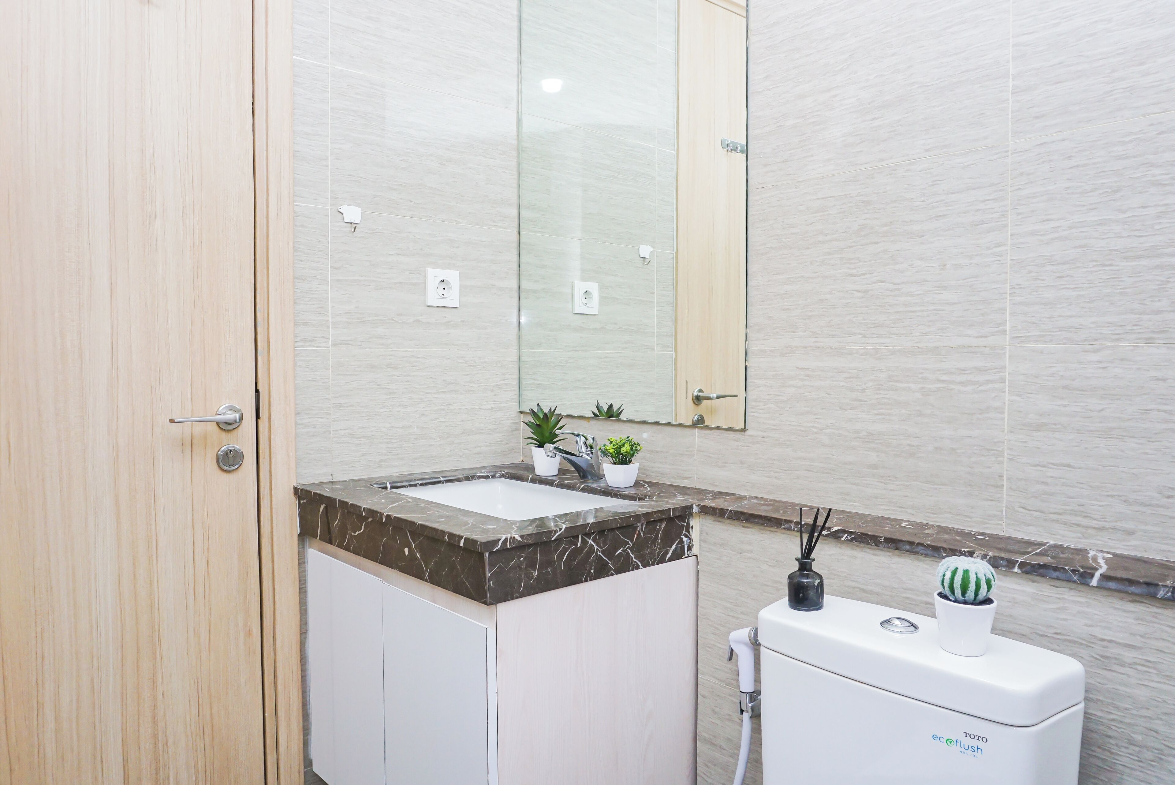 A modern bathroom with a marble sink, a toilet, and a mirror.