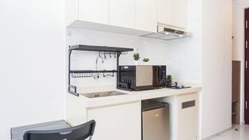 Uma cozinha compacta com micro-ondas integrado, uma pia pequena e uma máquina de lavar louça compacta.