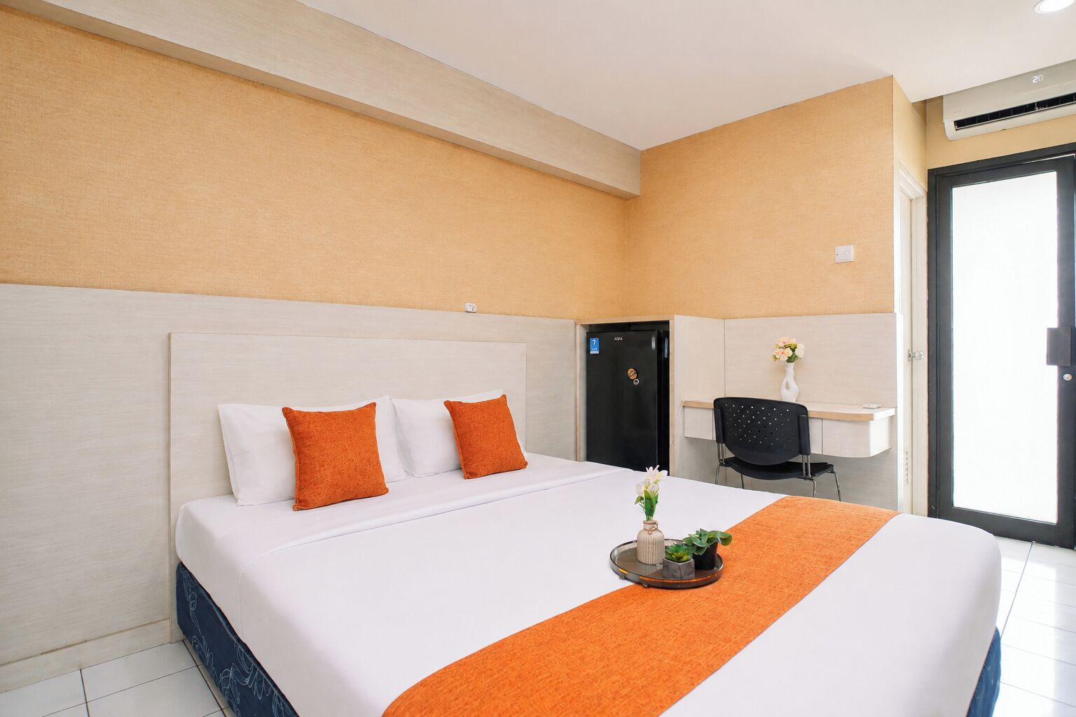 A hotel room with a bed, a desk, and a chair.