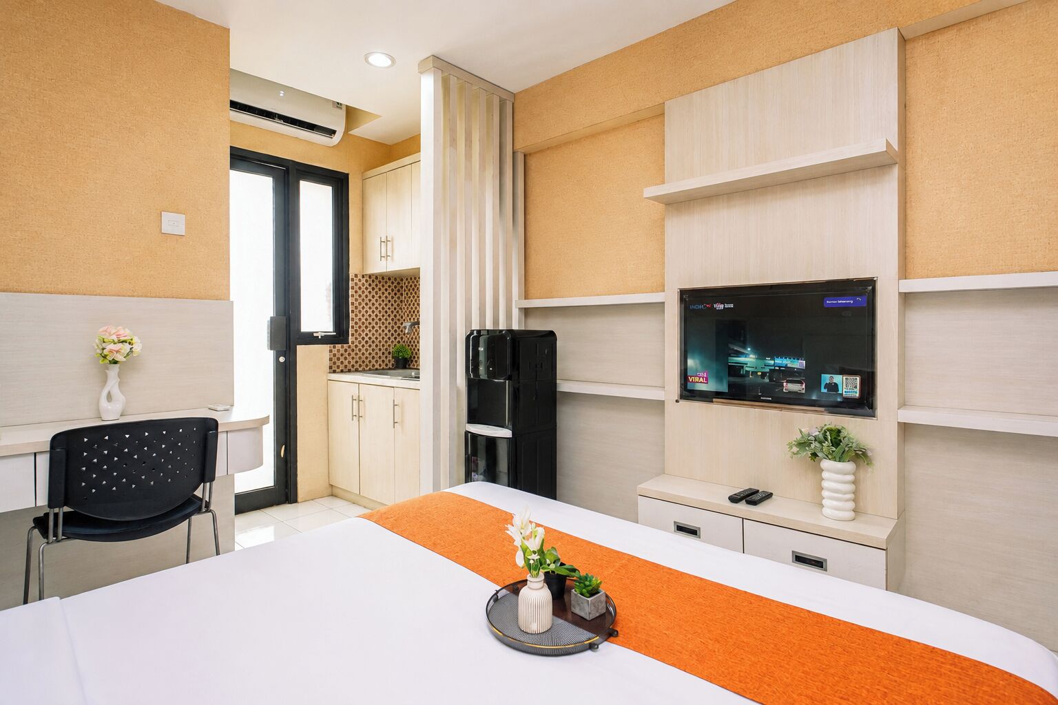 Une chambre d’hôtel équipée d’un lit, d’un bureau, d’une télévision et d’un mini-bar.