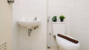 Un baño con lavamanos, inodoro y ducha blancos.
