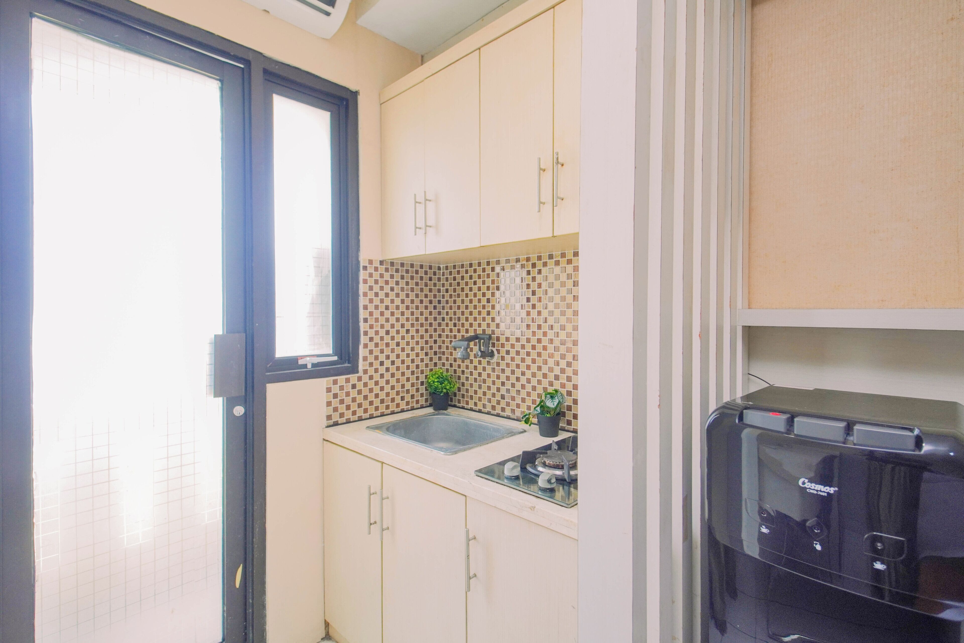 Cocina compacta con ventana, lavamanos y microondas.