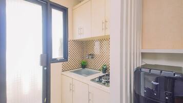 Cocina compacta con ventana, lavamanos y microondas.
