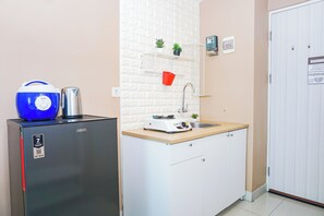 Eine kleine Küchenzeile mit Kühlschrank, Mikrowelle, Toaster und Spüle.