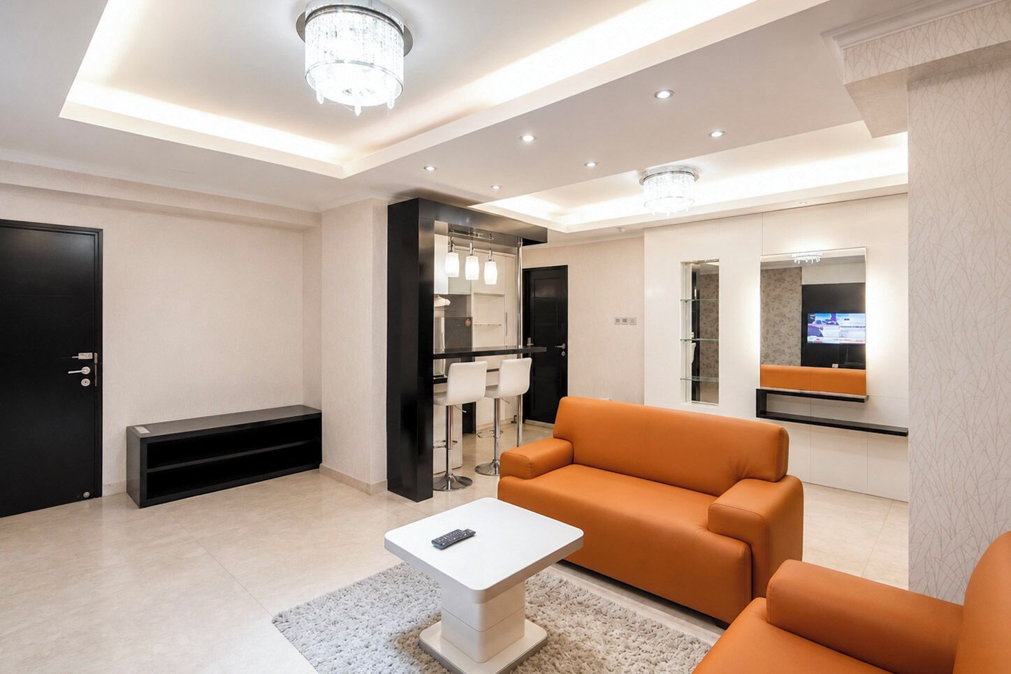 Un salon moderne avec un canapé, une table basse, un téléviseur et une salle de bain visible à travers une porte ouverte.