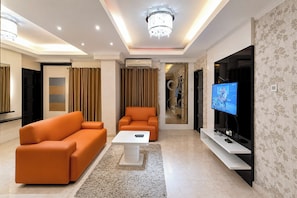 A modern living room with a sofa, a coffee table, and a TV. - Bright And Warm Combined 2Br At Apartment Suites @Metro (Bandung)