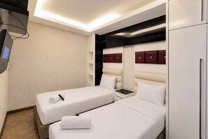 Ein Hotelzimmer mit zwei Betten, einem Nachttisch, einem Fernseher und einem Kleiderschrank.
