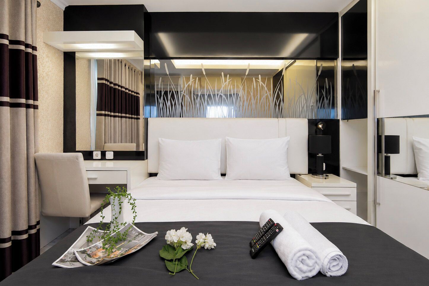A modern hotel room with a large bed, bedside tables, a desk, and a mirror.