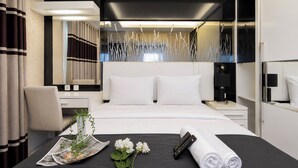 A modern hotel room with a large bed, bedside tables, a desk, and a mirror. - Bright And Warm Combined 2Br At Apartment Suites @Metro (Bandung)