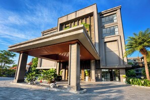 A modern building with a covered entrance, large windows, and a paved area with plants. - Serene 1BR Lavaya Nusa Dua Bali (Bali)
