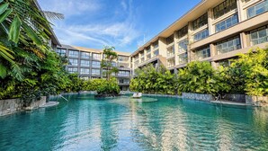 A hotel with a central swimming pool surrounded by lush greenery and modern architecture. - Serene 1Br With Nature View At Apartment Lavaya Nusa Dua Bali (Bali)
